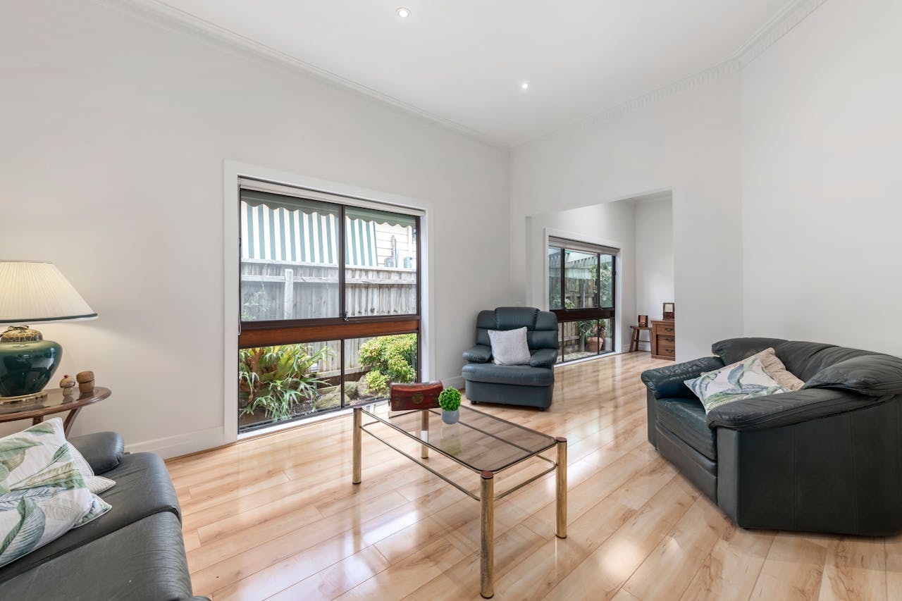 services-02 Bright living room with contemporary seating, wooden floors, and large windows letting in natural light.