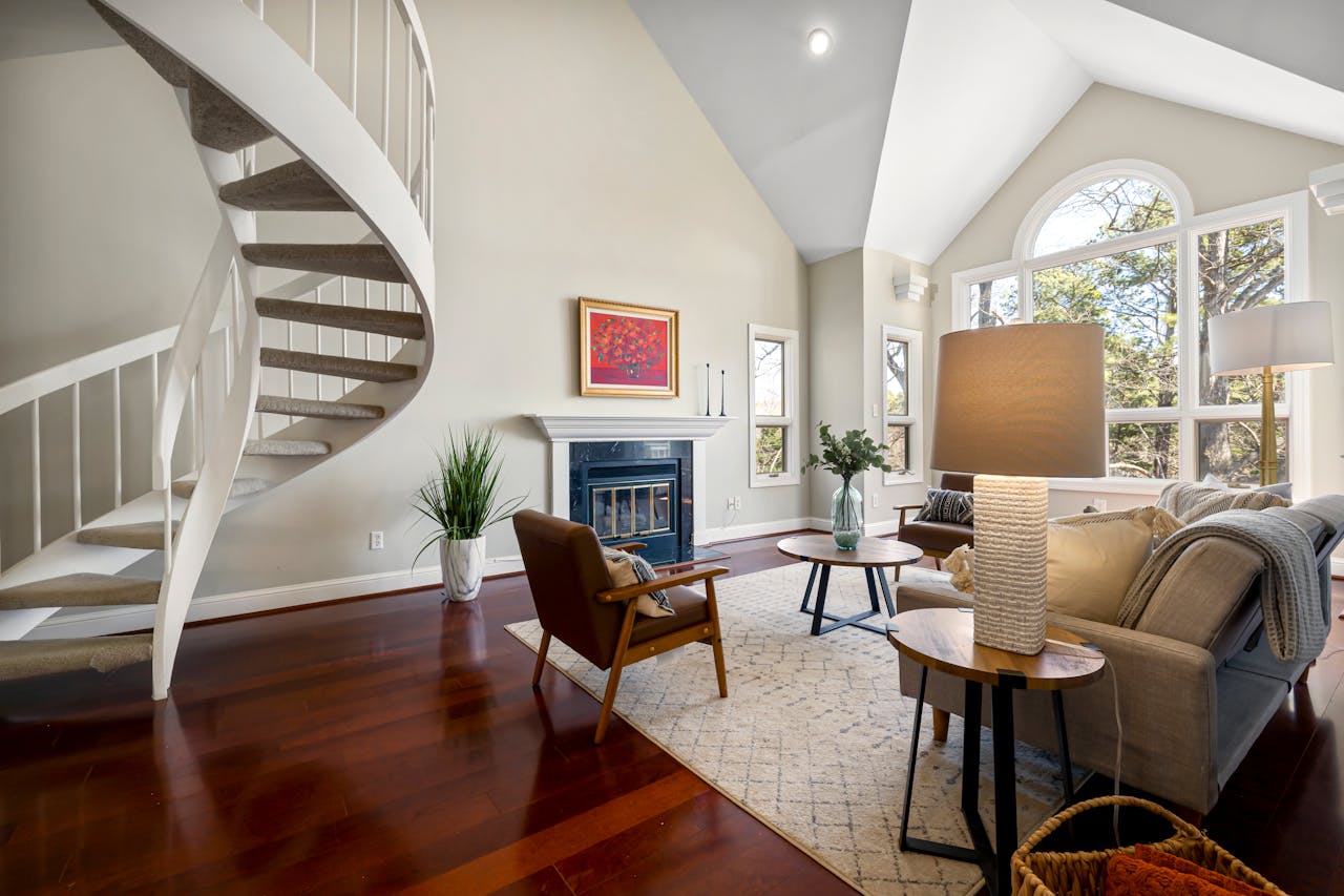 gallery-5 Inviting living room with spiral staircase, fireplace, and large windows, creating a bright and cozy atmosphere.